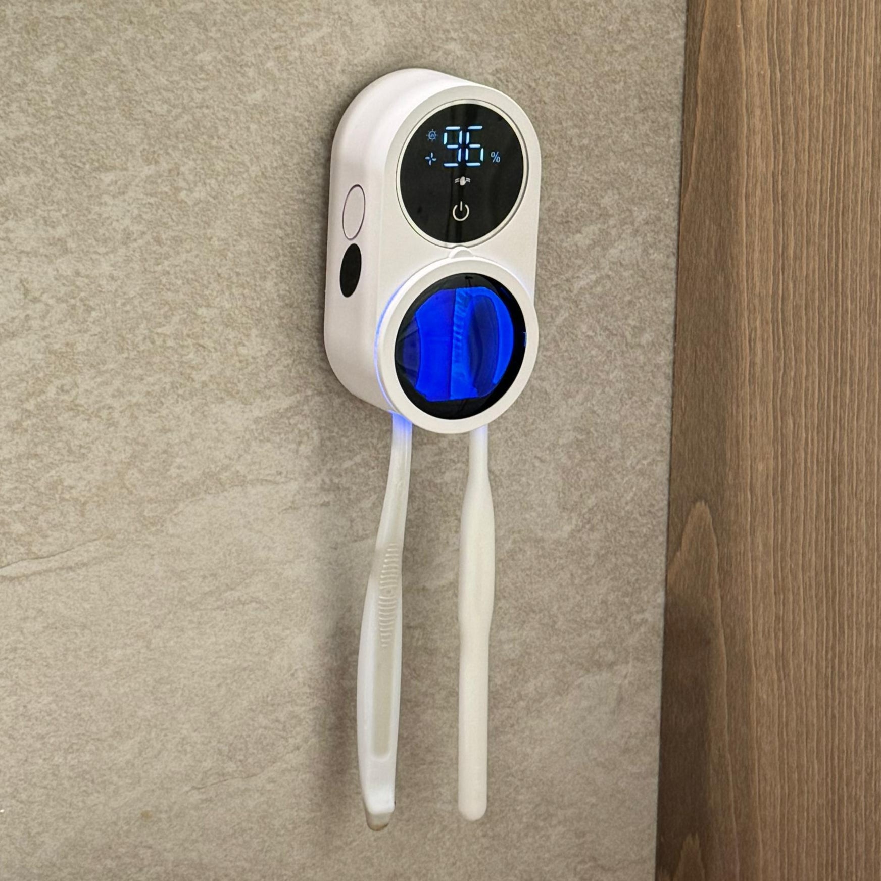 Digital temperature and humidity monitor on a bathroom wall next to a mirror.